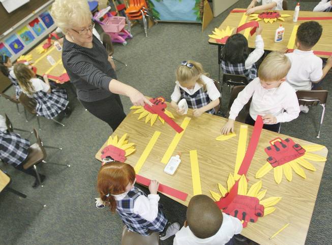 Meadows kindergarten teacher Linda Verbon, left, demonstrates how to make a dragon head out of construction paper to students, clockwise from bottom right, Nebi Samuel, 5, Daniel Johns, 5, Ainsley Wilson, 6, and Lindsey Hofflanders, 6, in preparation for the school's annual Chinese New Year event.