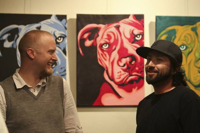 Graphic design student Jonathan Boyer jokes with figurative arts instructor Kevin Anderson, left, Thursday during the annual Juried Student Show at the Art Institute of Las Vegas.  Displayed on the gallery wall is "Prime Pits" by graphic design artist Steve Scott.
 