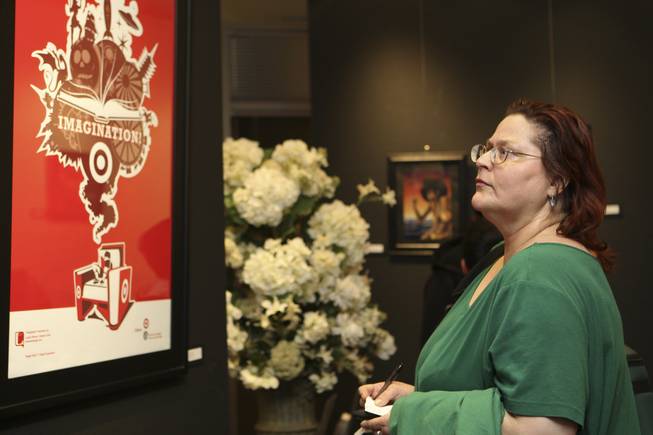 Graphic design artist Cheri Norton analyzes the graphic artistry of Landry Blume's "Imagination" during the annual Juried Student Show at the Art Institute of Las Vegas.  Commissioned by the City of Las Vegas, Blume's piece won second place in the institute's competition.
 