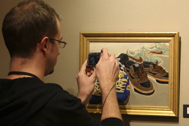 Graphic design artist Landry Blume takes a photograph of "Mommy Said They'll Take Me Anywhere" by artist Rick Quemado during the annual Juried Student Show at the Art Institute of Las Vegas.
