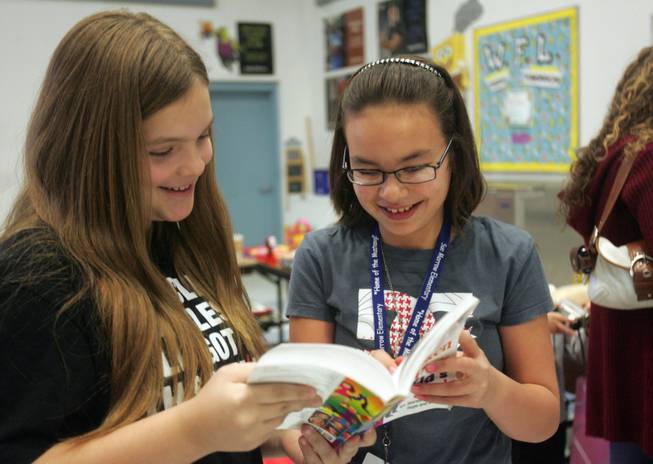 Gifted and Talented Education students Kaitlyn Guerin, left, and Sabrina Spurlock look through a book that was on sale at Morrow Elementary School's recycling sale Friday. Put on by the Gifted and Talent Education, know as GATE, students, the sale items were collected from all around the school.