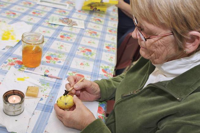 Writing with melted black wax, Patti Brewer, 70, draws flowers on an egg during the Ukrainian Easter egg craft class held at the Henderson Senior Center Tuesday.