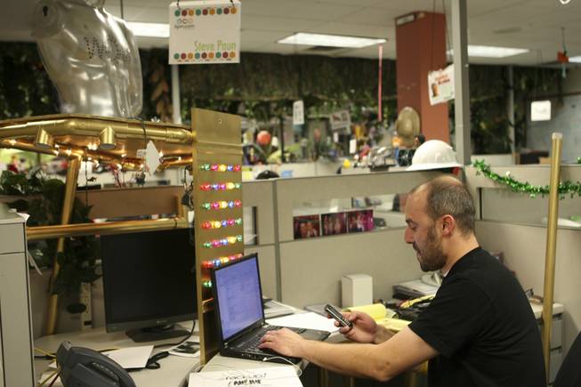 Zappos.com employee Steve Paun checks his phone while working at his desk that was decorated with lights and pipes as a prank.