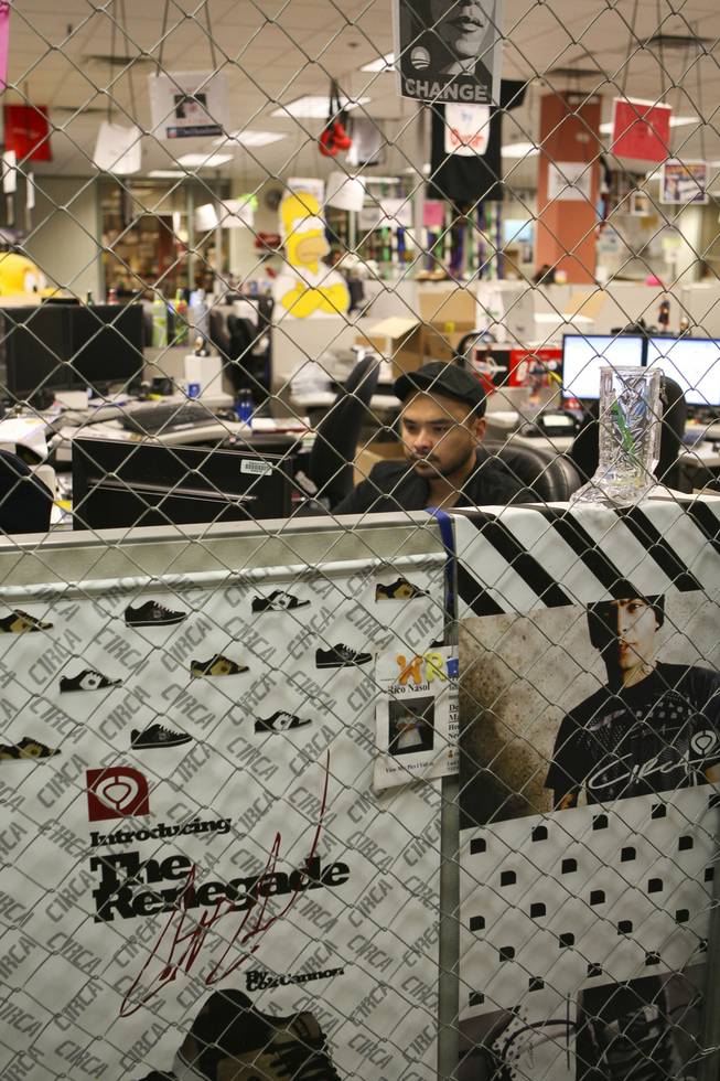 Rico Nasol, manager of the Zappos.com Web content team, sits at his desk surrounded by chain-link fencing and shoe posters at the company's corporate offices in Henderson.