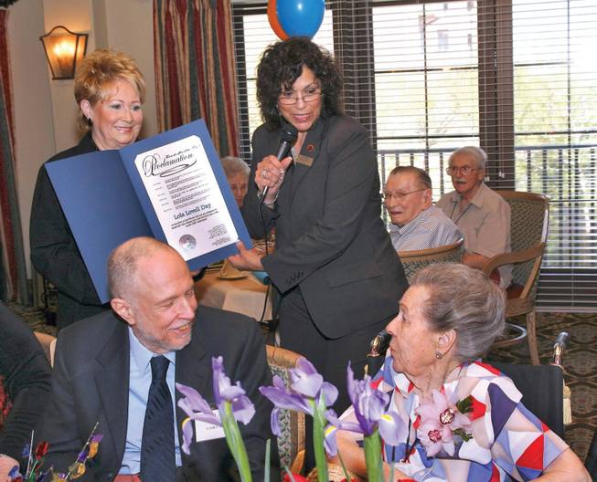 Activity Coordinator Maria Truelock, background right, and registered nurse Cheryl Newton, background left, present 100-year-old Lola Lovell, right, with a proclamation from Las Vegas Mayor Oscar Goodman as her son Bruce Lovell, left, looks on during a birthday celebration at Las Ventanas.