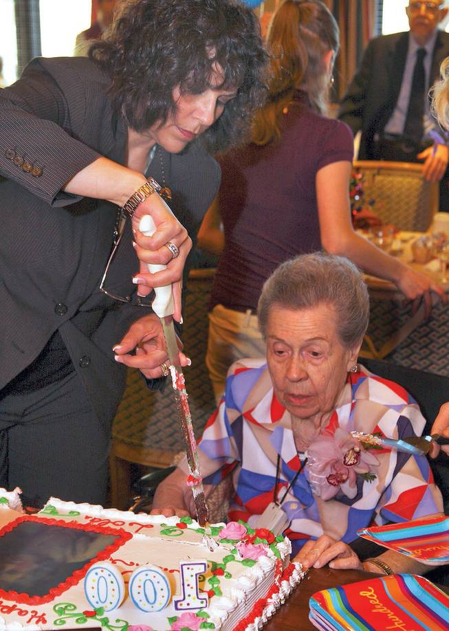 Activity Coordinator Maria Truelock, left, cuts the cake for Lola Lovell, right, during Lovell's 100th birthday celebration held at Las Ventanas.