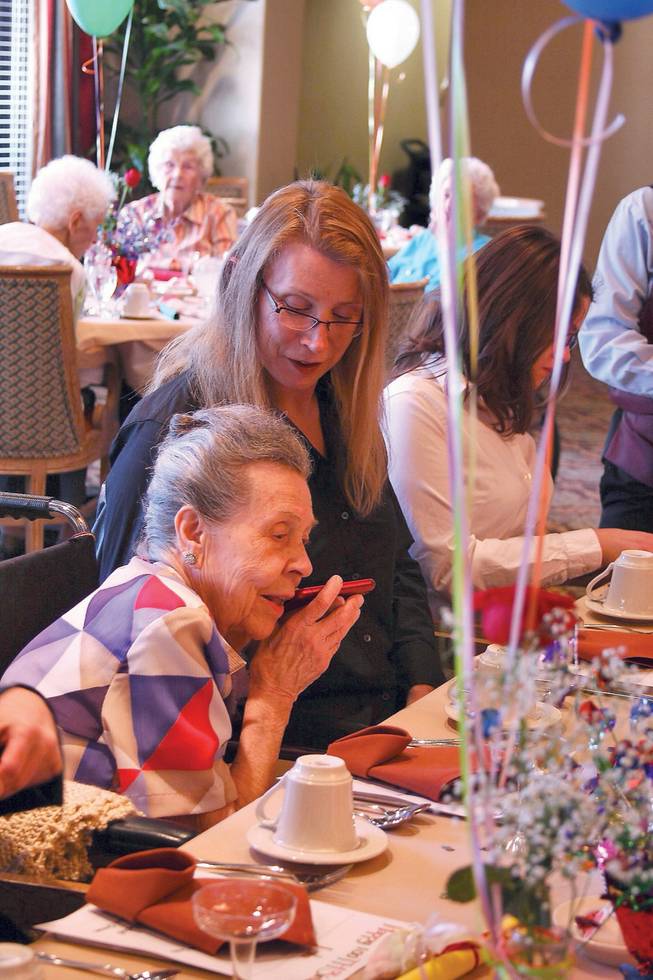 Centenarian Lola Lovell, foreground left, listens to a song playing on her granddaughter Marcie Lovell's cell phone during the birthday celebration for "Miss Lola" at Las Ventanas.