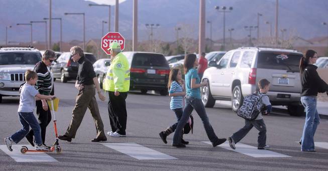 Children cross the street as they make their way home from Linda Givens Elementary School. To alleviate crowding, Givens might go to a year-round schedule. 