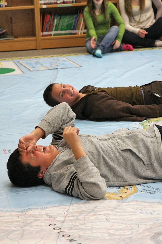 Eighth grader Colton Coss, front, laughs while he and classmate Branislav Klenovski each pose as an isthmus, or a narrow strip of land connecting two larger land areas, on National Geographic's map of North America.