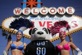 Showgirls Jennifer Gagliano, left, and Tala McDonnough, right, pose for a picture Wednesday with the Earth Hour panda bear at the Welcome to Fabulous Las Vegas sign.  Officials from the World Wildlife Fund joined Clark County Commissioner Lawrence Weekly, Las Vegas Mayor Oscar Goodman and Henderson Mayor James Gibson at the sign to officially kick off the Las Vegas Valley's participation in Earth Hour, a global event calling for action on climate change.  
