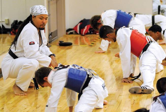 Tae Kwon Do instructor Terry Blackburn keeps a close eye on his students as they stretch out during the beginning of a practice session inside the Chuck Minker Sports Complex.