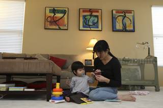 Ming Chu plays with her one-year-old daughter, Emma, on new carpet in the family room of their Seven Hills home, which they renovated after purchasing it in foreclosure.