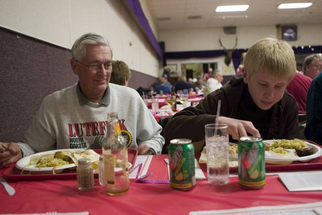 Ron Effertz, left, watches as his grandson, Kyle Effertz, right, starts on his dinner which includes lutefisk, a traditional dish made of whitefish that's either salted or dried. The family attended the 11th annual Lutefisk Dinner on Saturday at the Boulder City Elks Lodge.