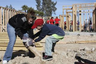 Tenth-grader Alissa Magness and fourth-grader Reagan McCoy, right, move rocks around the foundation of a house being built for Rosa Santana Saturday morning.