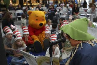 Children listen to The Scarecrow, played by Terri Hacker, read stories Saturday during the grand opening of Henderson Libraries' new branch inside the Galleria at Sunset Mall.