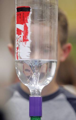 Riley Thompson, 8, watches as water twirls through a soda bottle like a tornado during John R. Beatty Elementary School's Jr. Engineering Day.