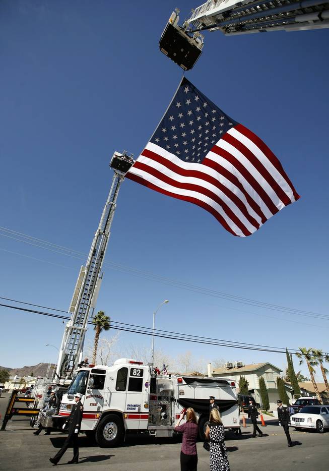 A paramedic engine from Henderson Fire Station 82 carries the coffin of 20-year veteran firefighter Jeff Mann through an archway of ladder trucks draping a United States flag in his honor during the final leg of a procession leading up to the Church of Jesus Christ of Latter-day Saints on Arrowhead Trail Wednesday.