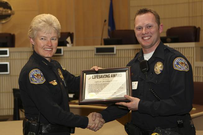 Officer Jeremy Leinan receives a Lifesaving Award for responding with an automated emergency defibrillator to a citizen, who had an apparent heart attack, from Henderson Police Chief Jutta Chambers Wednesday during the 6th Annual Commendation Award Ceremony.
