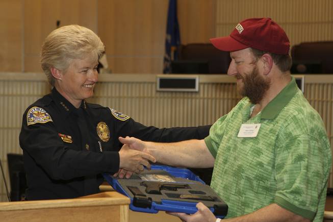 Retired Corrections Officer Mark Cathey receives a duty weapon for outstanding service from 1982-2009 by Henderson Police Chief Jutta Chambers Wednesday during the 6th Annual Commendation Award Ceremony.