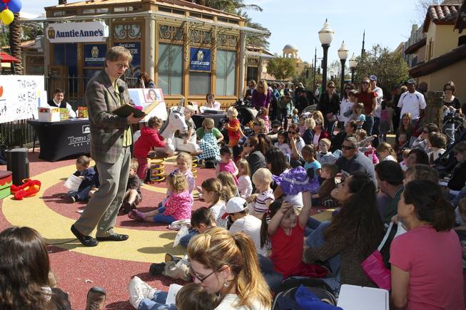 Children gather around Magician Mac King as he reads "Teeny-Tiny, An English Folk Tale" by Olive Beaupre' Miller during storytime Wednesday in Town Square plaza in celebration of National Reading Month.