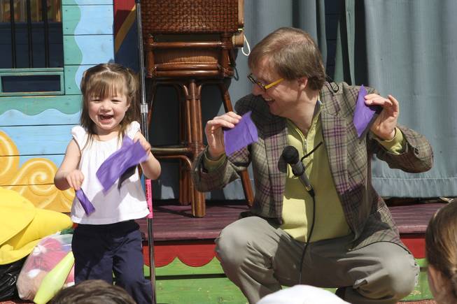 Cameryn Seaux, 2, laughs with Magician Mac King while trying to learn the trick of making an origami hat during storytime Wednesday in Town Square plaza in celebration of National Reading Month.