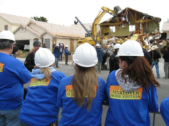 Volunteers huddle against the wind as they watch the demolition of the Cerda family's house for ABC's "Extreme Makeover: Home Edition" filming in Las Vegas this week.