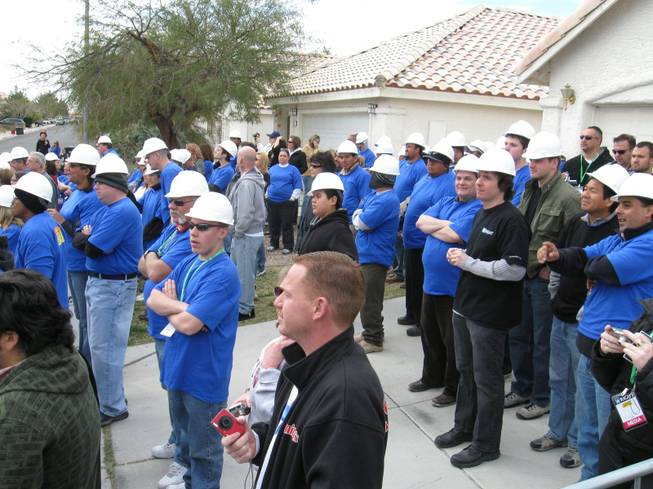 A slew of volunteers in blue await their turn to help as they watch the demolition of the Cerda family's house for ABC's "Extreme Makeover: Home Edition" filming in Las Vegas this week.