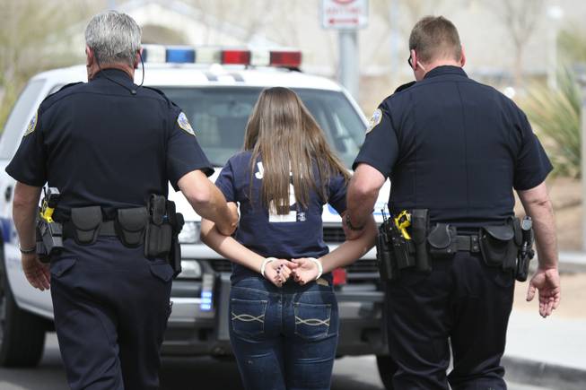 During the Every 15 Minutes program at Liberty High School, Henderson Police officers Joe Roy and Eron Bushell, right, escort senior Alexa Kelly to a patrol vehicle Thursday after being placed under mock arrest in a mock alcohol-related car accident.
