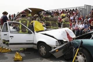 After cutting the roof off a vehicle during the Every 15 Minutes program, Henderson firefighter paramedics rush to the aid of Liberty High seniors Ali Fragoso and Nadia Cedillo-Quintero, who are trapped in the vehicle of a mock alcohol-related car crash at Liberty High School.