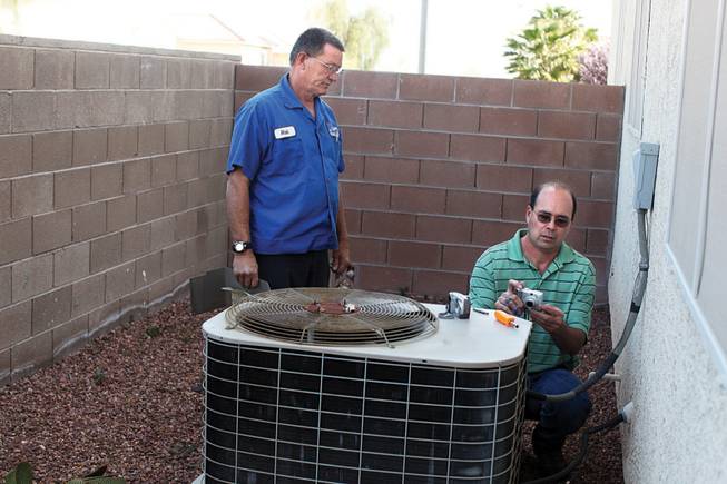 
Technician Rich Parker, left, and Jack Ramsay of Sierra Air Conditioning check out a unit at a house involved in a lawsuit. Ramsay is there because he received notice from the builder, which had received a letter from the homeowner's attorney complaining of problems.