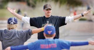 Al Kermode, coach of the Little League Diamond Backs, leads his team in some stretching exercises during a morning practice at the Boulder City Veterans Memorial Park ball fields.
