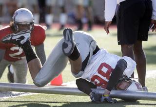 Wide receiver Aaron Reed (86) falls into the leg of a portable goal post after Sidney Hodge, left, (23) broke up a pass reception in the end zone during the first scrimmage of the season at Rebel Field on UNLV campus Friday, March 26, 2010. 