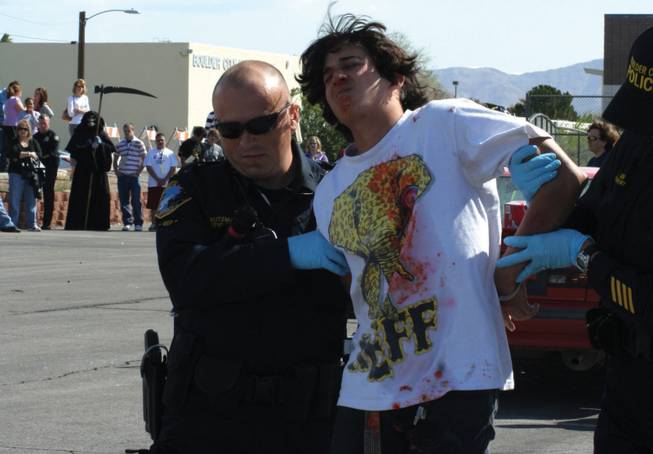 Justin Jensen is handcuffed by Boulder City Police during a mock crash that was put on Thursday at Boulder City High School. Every 15 minutes someone dies from a DUI related accident. In the back stands the Grim Reaper as a physical representation of how many people died within the time the students were watching the simulation.   
