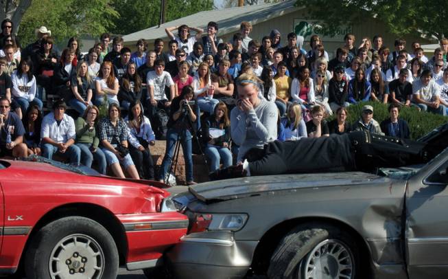 Students from Boulder City High School watch a mock DUI crash on Thursday. Stephanie Boyle, a senior, makes the 911 call while Zack DeSilva, one of the victims, who was projected through a window, lies on the hood of a car.