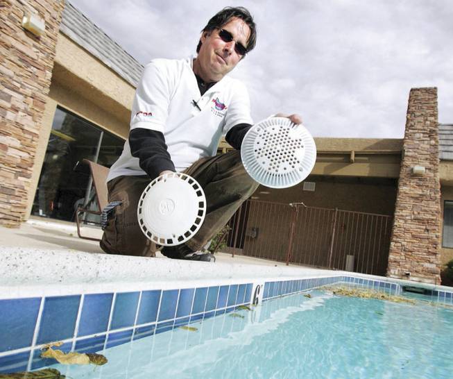 Mike Heiney, owner of Westside pools, compares an old pool drain cover, left, with a new anti-entrapment cover designed to prevent death. Federal law requires that public and community pools and spas have the drain covers installed, which Heiney calls "an expensive process."