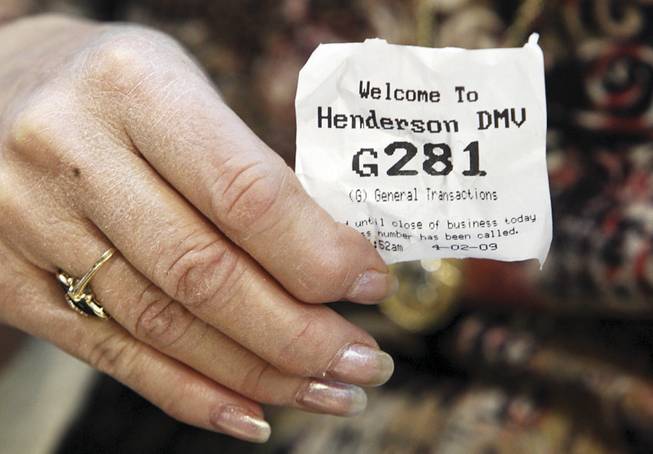 A woman shows her number as she waits at the Department of Motor Vehicles in Henderson, where average wait times are longer than a year ago.