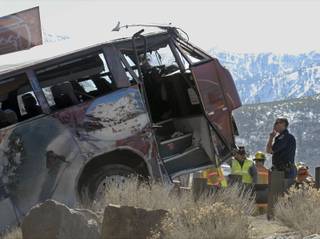 A California Highway Patrol trooper checks the front of a bus carrying employees from Reno to Squaw Valley that rolled on I-80 Saturday near Floriston, Calif.  An accident involving a resort's employee shuttle bus on the main highway through California's rugged Sierra Nevada killed one person and injured 27 others, one of them critically and six seriously, authorities said.