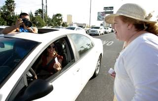Paula Gray is photographed by tourists while handing out her resume to motorists on the Sahara Avenue off-ramp of northbound I-15 Thursday, April 9, 2009. 