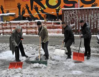 In this photo released by CBS, members of the band U2, from left, Adam Clayton, The Edge, Bono and Larry Mullen Jr. shovel snow on Monday March 2, 2009 on 53rd street outside the Ed Sullivan Theater prior to their appearance on the 