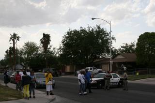 Residents watch as Metro Police officers investigate a homicide on Sunrise Avenue, near the intersection of Charleston and Lamb boulevards.