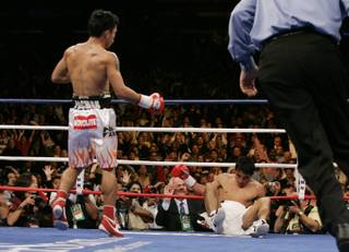 Manny Pacquiao (left), of Philippines, sends Erik Morales, of Mexico, to the mat for the third time during their super featherweight fight at the Thomas & Mack Center in Las Vegas, Nevada on November 18, 2006.
