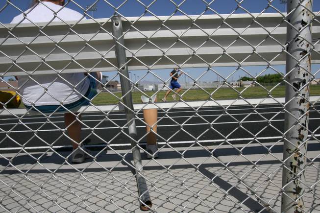 Boulder City High freshman track athlete Danyell Harding sits in the bleachers at the school's track last week while her prosthetic limb is at right in this photo illustration.
