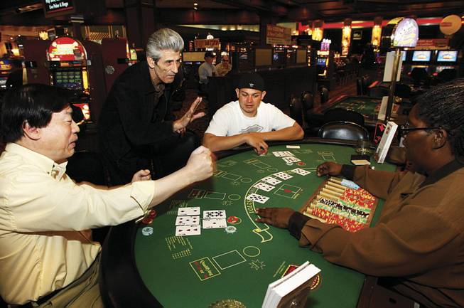 George Boutsifakos, center, co-creator of Two Cards High, advises dealer Phyllis Carter as Stanleu Ko, left, and Jesse Delgado play the game during its test run in April at Boulder Station. 