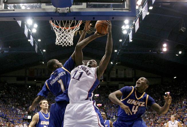 Kansas' Quintrell Thomas (11) gets past UMKC's James Humphrey (1) and Latreze Mushatt (4) to put up a shot during the first half on Nov. 16, 2008, in Lawrence, Kan. Thomas announced his intent to transfer to UNLV on May 22, 2009.