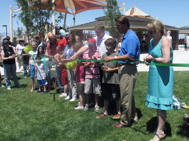 Officials from the City of Henderson and Pulte Homes join local children and parents Saturday in cutting a ribbon to signify the opening of Madeira Canyon Park.