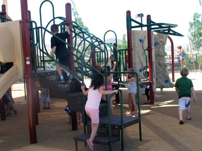Children play on one of Madeira Canyon Park's two play structures during the grand opening celebration of the park Saturday.