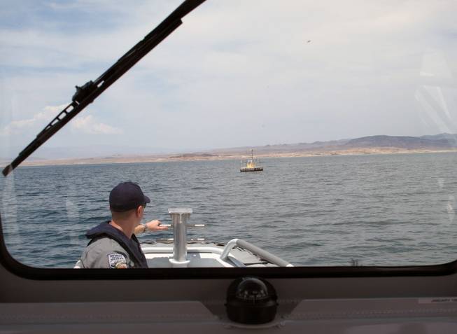 Game Warden Randy Bond looks at a weather station on Lake Mead from the bow of a Department of Wildlife boat on Friday.
