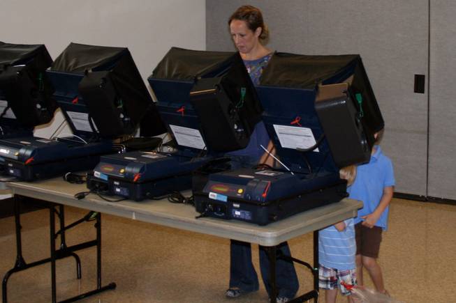Catherine Nooda casts her ballot at Valley View Recreation Center in Henderson while her sons, Cooper and Brennan, look on.