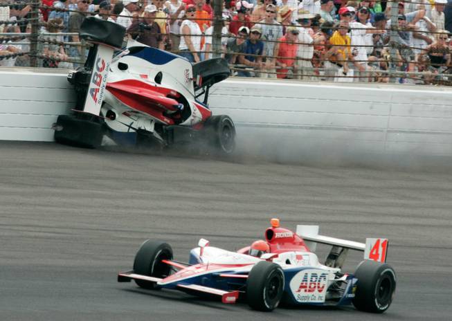Vitor Meira, of Brazil, crashes into the wall as his teammate A.J. Foyt IV passes by during the Indianapolis 500 auto race at Indianapolis Motor Speedway in Indianapolis, Sunday, May 24, 2009.
