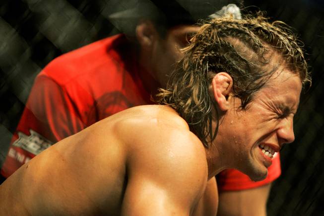 Urijah Faber grimaces before the fourth round against Mike Brown in a World Extreme Cagefighting featherweight world title mixed martial arts fight on Sunday, June 7, 2009, in Sacramento, Calif. Brown won by unanimous decision to retain his championship, while Faber suffered a broken hand in defeat.